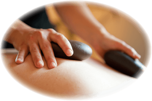 Two hands holding hot stones on the back of someone getting a massage